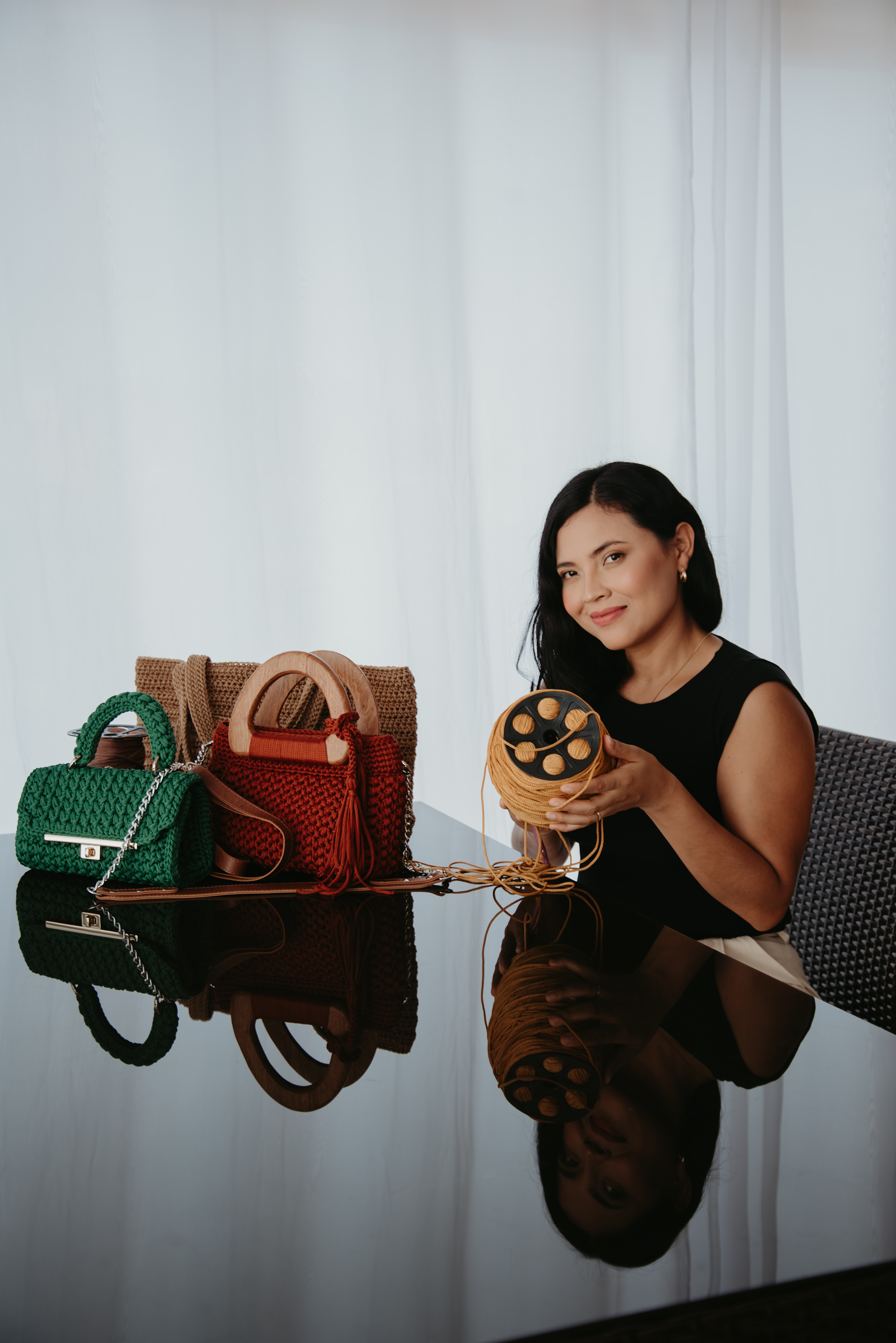 Êdi criadora de bolsas de crochê artesanais segurando um novelo de fio