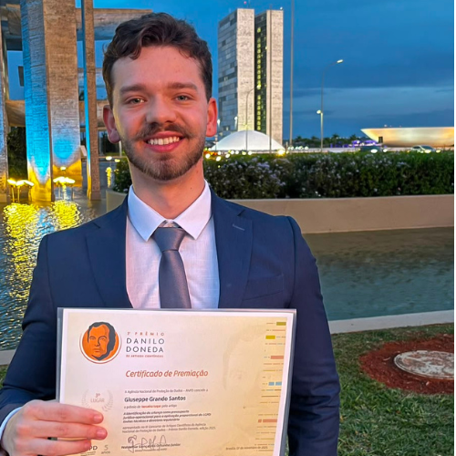 Giuseppe Grando com o certificado do 3º Prêmio Danilo Doneda da ANPD, em frente ao Congresso Nacional